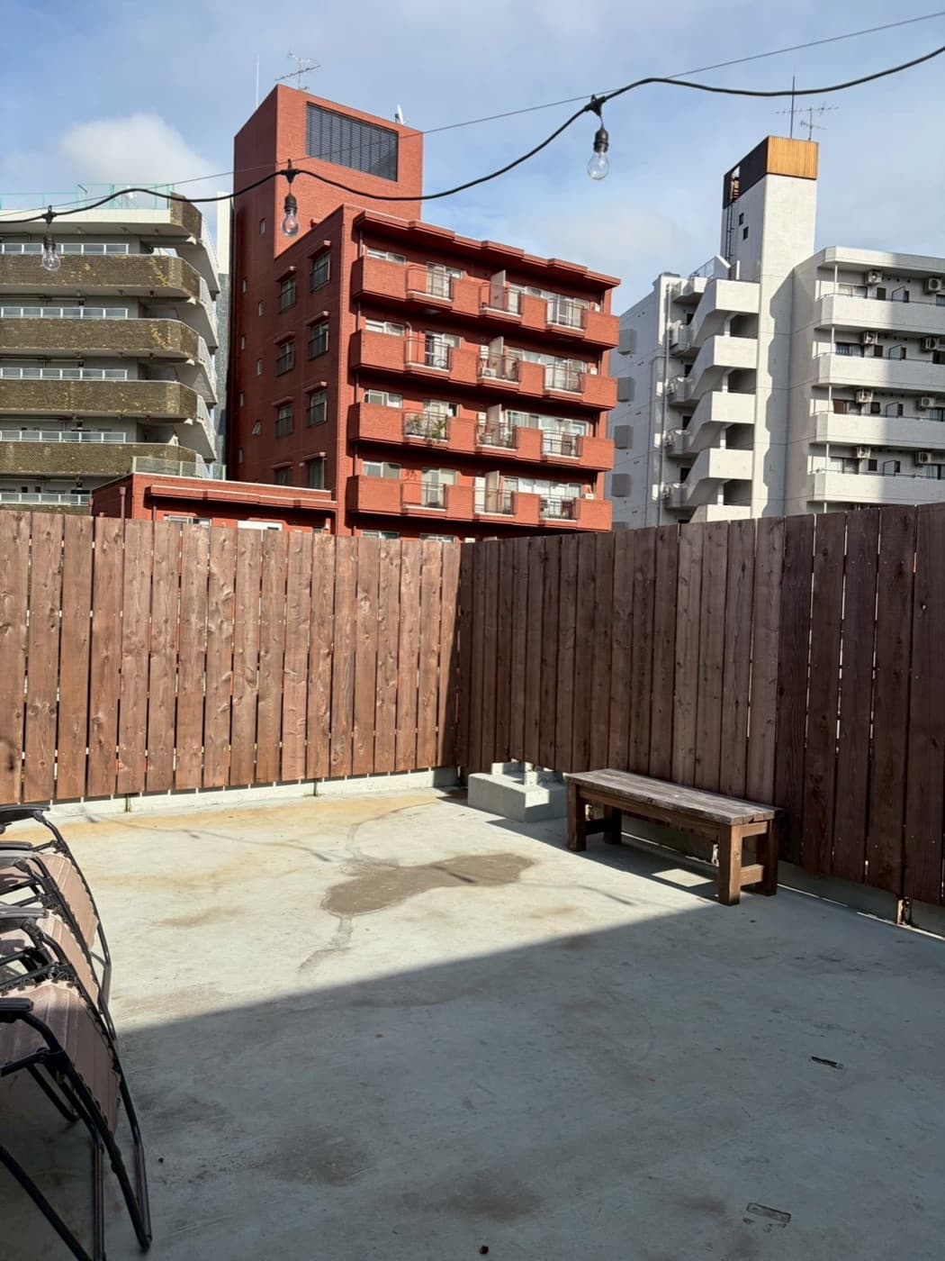 Outdoor terrace of the venue with a wooden fence and bench, Nakameguro buildings behind